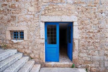 Stone old building with blue wooden vintage door and windows.