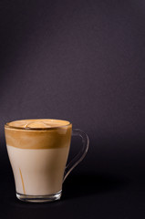 Dalgon iced coffee in a transparent glass on a dark background. Korean and indian whipped coffee, copy space, vertical image