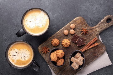 Two cups with coffee, brown sugar and various sweets on stone background. Top view. Copy space