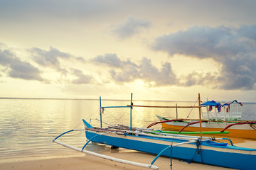 Beautiful colorful sunrise on the seashore with fishing boats. Philippines, Siargao Island.