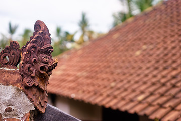 Slightly damaged traditional balinese roof decoration in a shape of a head of mystical being.