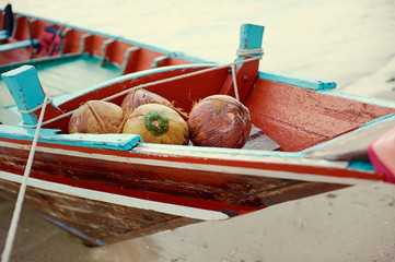 Coconuts on a frontal part of the docked boat on a sandy shore.