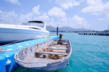 Koh Samui blue-coloured pier with docked boats and yachts on it.