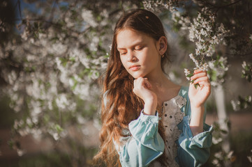 beautiful young girl with long flowing hair in a blooming cherry blossoms garden