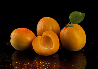 Apricots with green leaves on a black background.
