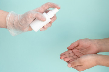 hand in medical glove holds white bottle of antibacterial sanitizer for child hands to treat hands with an antiseptic, protection from epidemic, viruses, sars, coronavirus, healthcare concept