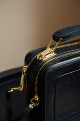 close up view of leather handbag with golden zippers on beige background