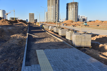 Fototapeta premium Laying paving slabs and borders at construction site. Process of installing paving bricks in the town pedestrian zone. Screeding the sand for install concrete blocks. Road works on pavement renovation