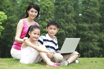 Mother and children using laptop in the park