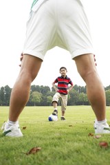 Father and son playing soccer in the park