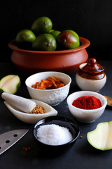 Homemade Raw green mango pickle. Preparation for spicy Kairiche lonche or aam ka achar. Ingredients at background such as, raw mango, salt, red chili powder, oil and fenugreek seeds. copy space. moody