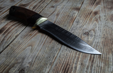 Close-up of a Damascus steel hunting knife on a wooden table