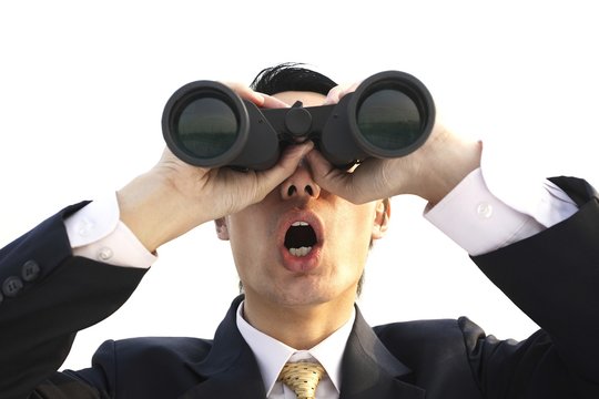 Businessman in shock while looking through a binoculars