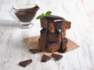 Slices of delicious brownie in a stack and poured with chocolate.