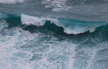 Blue and white breaking ocean wave seen from above