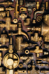 Brass scrap metal: taps, tees, plugs and various plumbing parts, spare parts. Against the background of a copper sheet. Close-up.