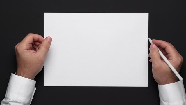 top view of a blank sheet of paper and a businessman's hands on a black table, white shirt and wrist watch