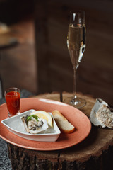 oyster with lemon on ice, next to spicy sauce and champagne