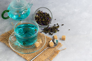 Obraz na płótnie Canvas A cup of hot, blue tea with pea flowers. Blue peas. For healthy drinking, detoxifying the body. Gray background.