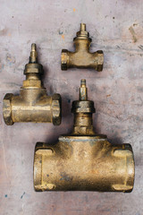 Brass scrap metal: taps, tees, plugs and various plumbing parts, spare parts. Against the background of a copper sheet. Close-up.