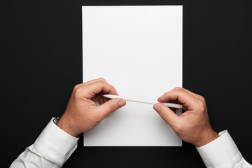 a blank sheet of paper and a businessman's hands on a black table, a white shirt and a wrist watch,...