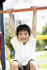 Fototapeta premium Boy hanging on monkey bars at playground