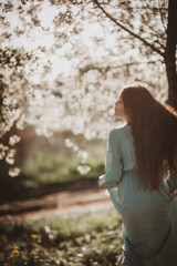 beautiful young girl with long flowing hair in a blooming cherry blossoms garden
