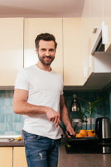 Handsome man smiling at camera while cooking breakfast in kitchen