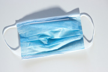 blue used medical mask with light shadows and lights on a white and gray background