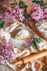 Homemade Apple pie on a wooden table next to a bowl of lilacs. Gentle toning.