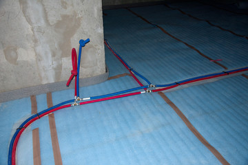 Naklejka premium Red and blue plastic pipes for cold and hot water of the main supply home water system. Water plumbing heating tube coming out under floor in a under construction building. Thermal work