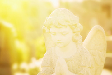 Ancient statue of beautiful guardian angel in sun rays