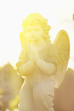 Ancient statue of beautiful guardian angel in sun rays. Vertical image.