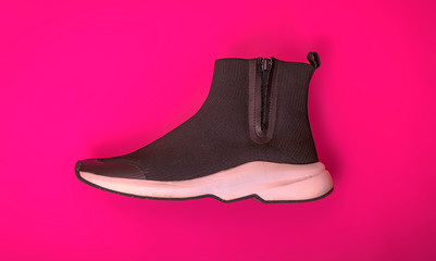 Beautiful fashionable socks sneakers on a pink background. Minimal design of . Stylish black sneakers. Training time concept.