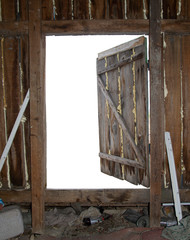 Old open wooden door with empty white space behind. Abandoned attic wooden wall with garbage as a template for backspace background placement.
