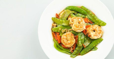 Stir-fried peas, put shrimp in a white plate on a white background.