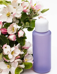 Lilac cosmetic bottle with pear flowers on a white background. Natural organic cosmetics concept.