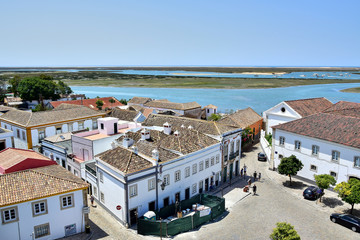 Faro / Algarve, Portugal: View from the observation deck of the Cathedral of Faro, the old city, white buildings with a brown tiled roof, small lakes, sea, in the summer during the daytime.