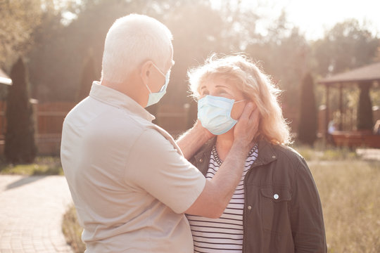 Beautiful Senior Couple In Love Wearing Medical Mask To Protect From Coronavirus Outside In Spring Or Summer Nature, Coronavirus Quarantine