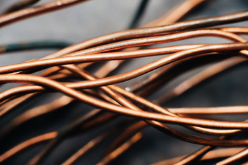 Copper scrap metal, wire, windings of motors and transformers, electrical wire without insulation. Against the background of a copper sheet. Close-up. Macro.