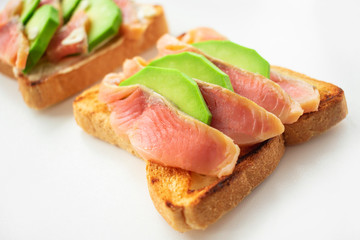 Avocado and salmon sandwich on toasted bread close up