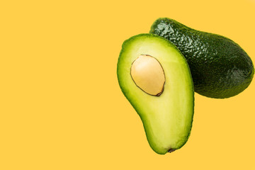 Two halves of avocado with a stone on a yellow background
