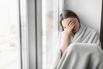 COVID-19 fever woman touching forehead in pain feeling tired. Coronavirus symptoms include, fever, cough, respiratory breathing difficulty, in more severe cases, pneumonia.