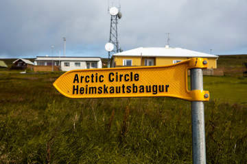 
landscape with the port of the island of grimsey in the north of iceland, off the arctic circle. A yellow sign indicates the direction to follow towards the crossing of the polar circle.