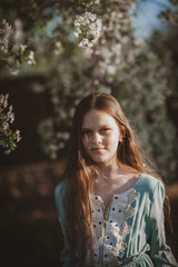 Naklejka premium beautiful young girl with long flowing hair in a blooming cherry blossoms garden