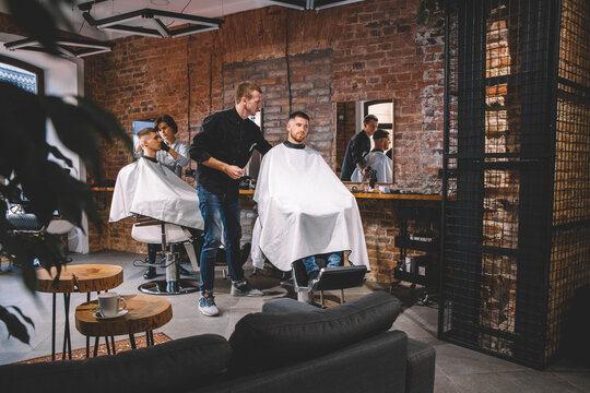 Hairdressers cut their clients in barbershop. Advertising and barber shop concept