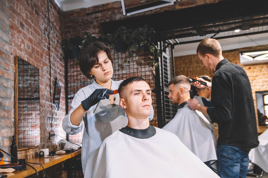 Hairdressers cut their clients in barbershop. Advertising and barber shop concept