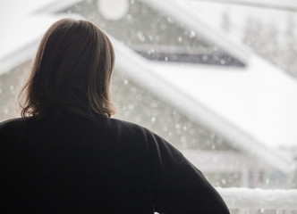 woman looking out snowy window