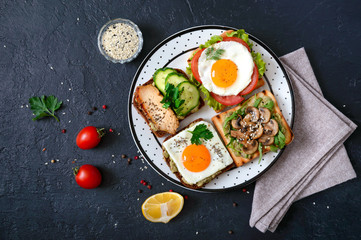 Different sandwiches on a black background. Tasty healthy appetizer with avocado. Quick breakfasts. Healthy eating concept. Proper nutrition. Top view
