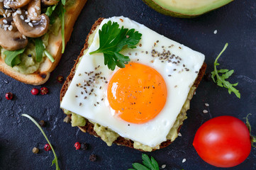 Rye toasts with mashed avocado, fried egg, fresh tomato, herbs. Tasty breakfast. Proper nutrition. Sandwich with egg. The top view